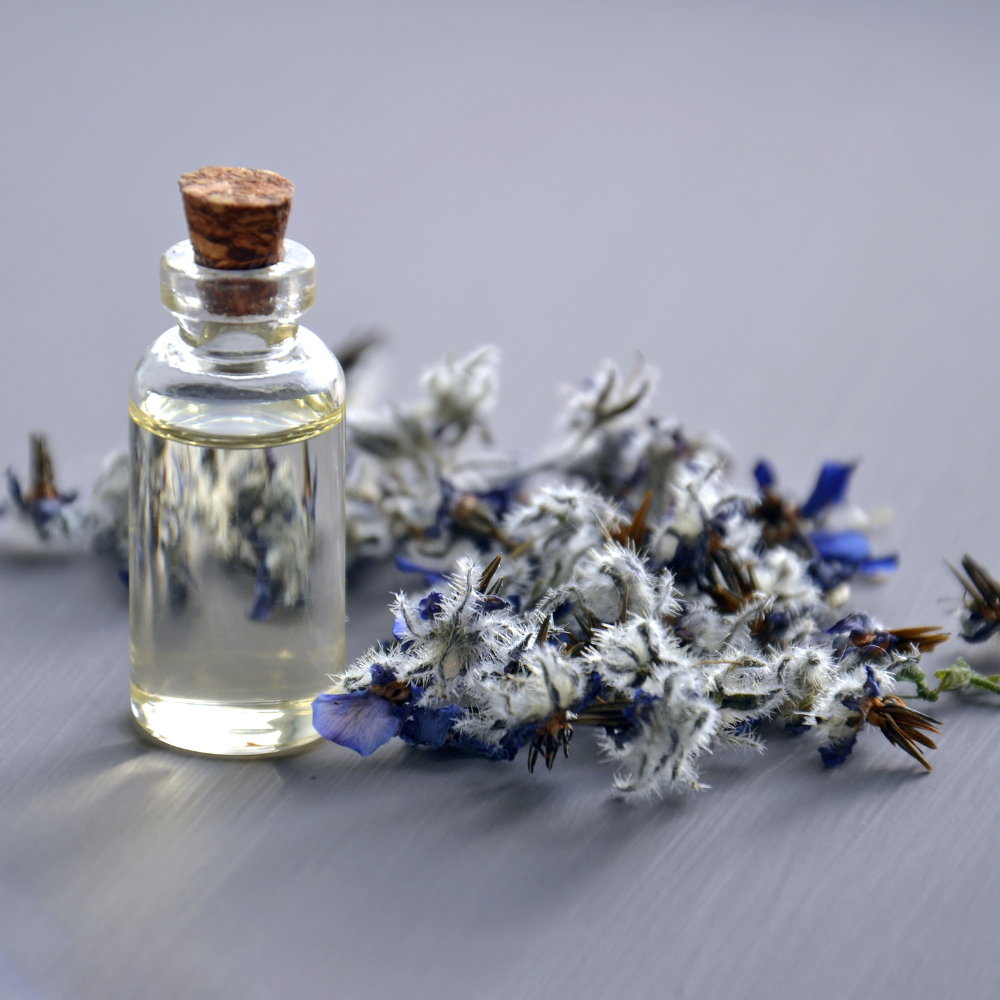 A bottle of oil on a table with blue and white flowers