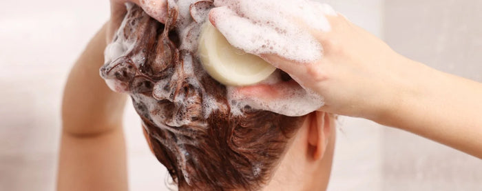 Une femme qui se lave les cheveux avec un savon